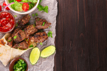 Pieces of shish-kebab on wooden table, top view