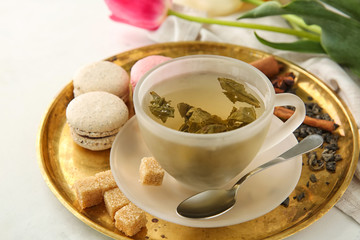 Tray with cup of hot tea and macarons on table