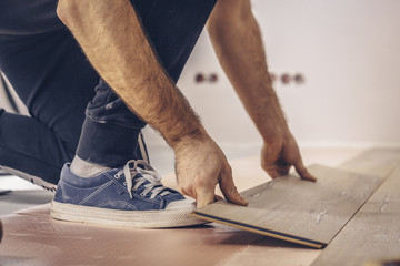 Working with hands installs a laminate board, professional flooring installation
