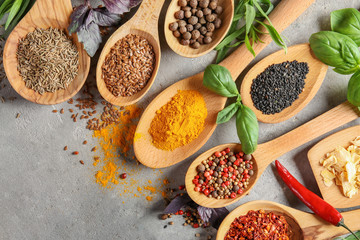 Variety of spices in spoons on grey background