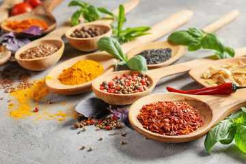 Variety of spices in spoons on grey background
