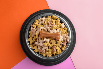 Bowl with pet food on color background
