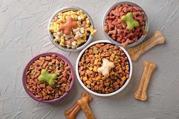 Bowls with pet food on grey textured background