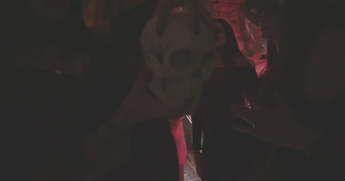 Young vampire woman holding skull and dancing at Halloween party