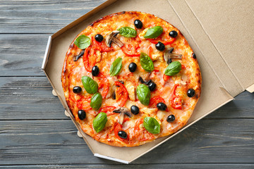 Box with tasty Italian pizza on wooden table