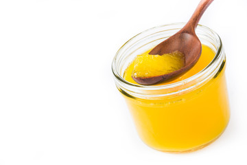 Ghee or clarified butter in jar and wooden spoon isolated on white background. Copyspace