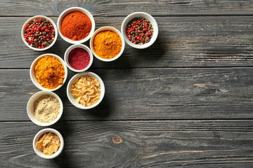 Bowls with various spices on wooden background