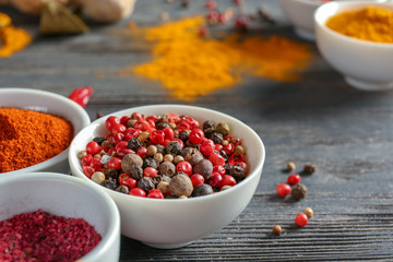 Bowl with mix of peppers on wooden background