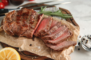 Board with tasty grilled steak on table