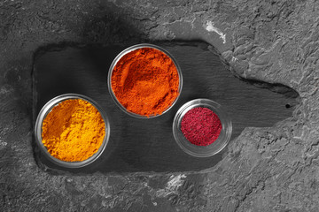 Bowls with various spices on slate plate, top view