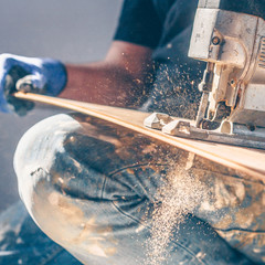 The electric jigsaw in the hands of the worker, the sawdust and dust are flying beautifully,...