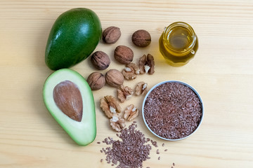 Healthy omega 3 food, walnuts, olive oil, avocado and flaxseed on wooden background