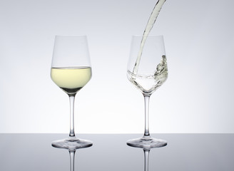 White wine pouring in glass on gray background