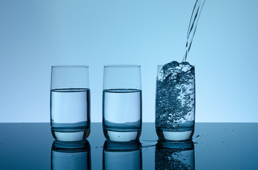 Creative splashing water in the glass on blue background
