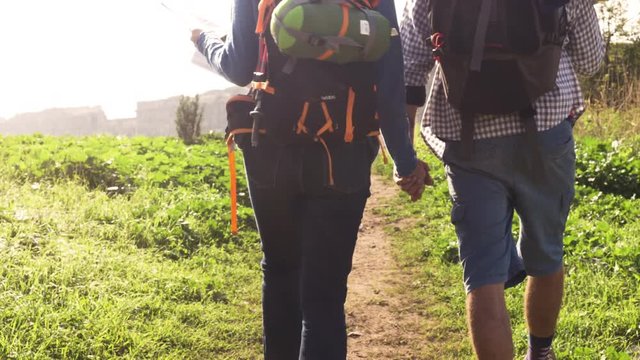 Young lovely couple backpackers tourists walking holding hands toward roman aqueduct arches in parco degli acquedotti park ruins in rome on romantic misty sunrise with guitar and sleeping bag slow