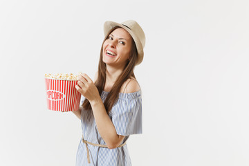 Young woman in blue dress, hat watching movie film holding eating popcorn from bucket isolated on white background. People, sincere emotions in cinema, lifestyle concept. Advertising area. Copy space.