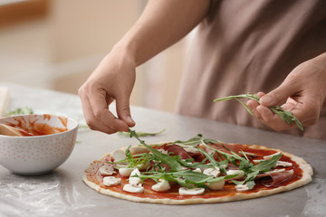 Woman preparing pizza at table in kitchen