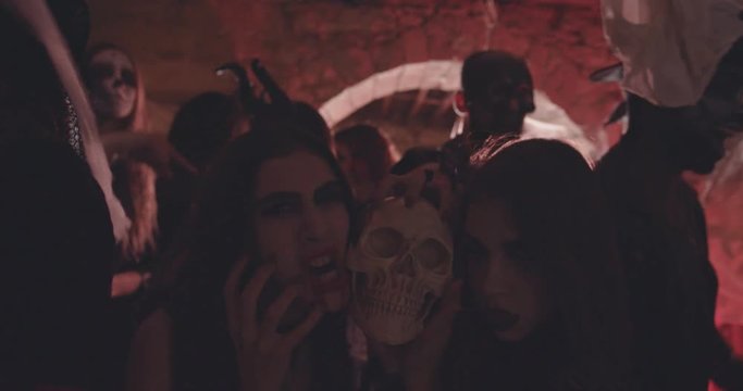 Women in gothic Halloween costumes holding skull at dress-up party
