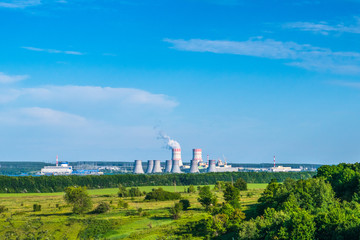Fototapeta na wymiar Nuclear power plant with green field and blue sky