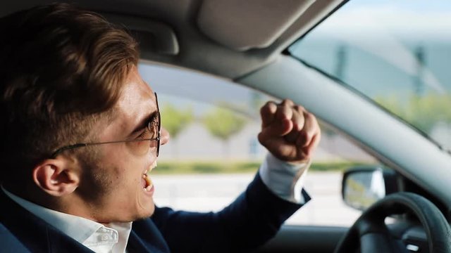 Depressed and very upset young businessman in the car. A man drinks alcohol at the wheel problems in business or personal life