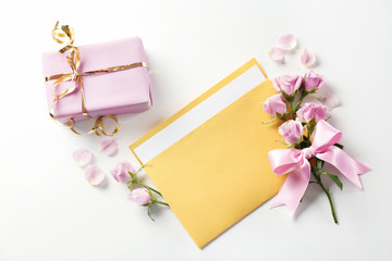 Open mail envelope with flowers and gift box on white background
