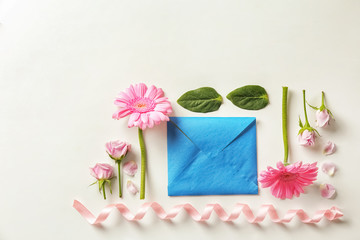 Flat lay composition with flowers and envelope on white background