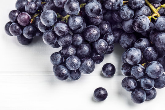 A Cluster Of Strawberry Grapes On A White Wooden Background.