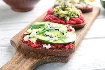 Board with tasty toasts on wooden background