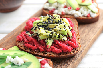 Board with tasty toasts on wooden background, closeup