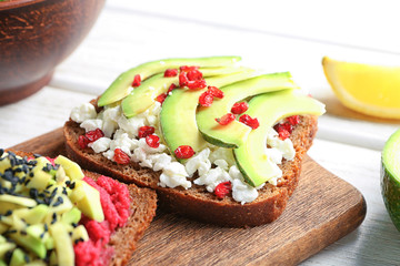 Board with tasty toasts on wooden background, closeup