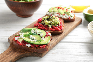 Board with tasty toasts on wooden background