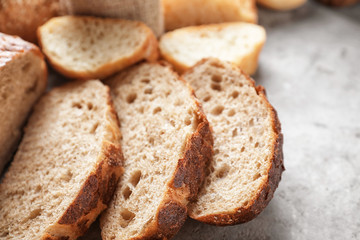 Sliced tasty bread on grey background, closeup