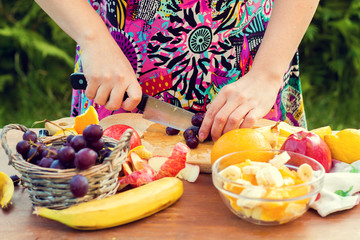 woman in the garden cuts fruit salad