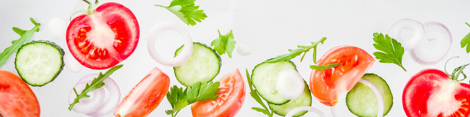 Creative background, layout, concept of fresh healthy diet of salad, fresh raw  vegetables tomatoes parsley onions cucumbers greens, simple pattern on white background