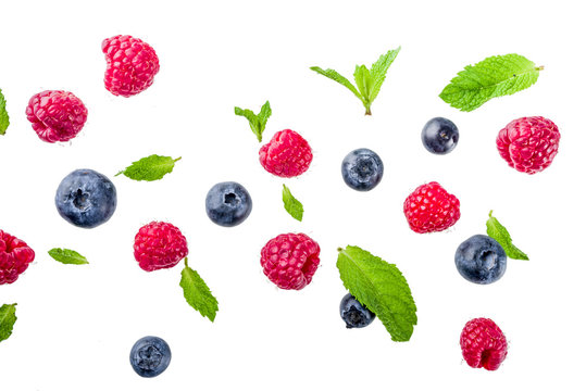 Creative layout, background, with fresh berries, simple pattern on white background. Raspberry, blueberry, mint leaves, slices of lemon.