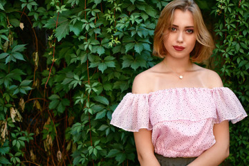 young woman, against background of summer green park, green leaves