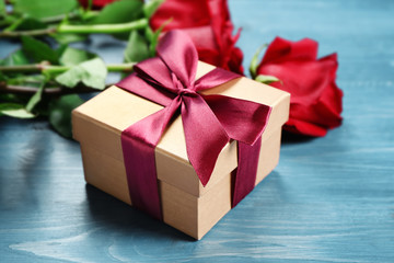Gift box and beautiful roses on wooden background