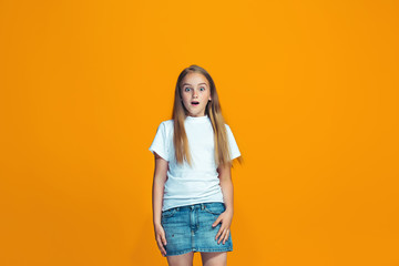 Beautiful teen girl looking suprised isolated on orange