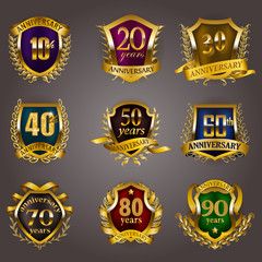 Set of gold anniversary badges with laurel wreaths, shield, numbers. Decorative emblem of jubilee on gray background. Filigree element, frame, border, icon, logo for web, page design in vintage style