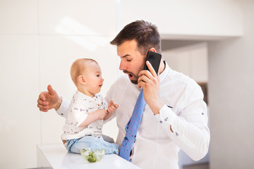 A baby boy making his fathers tie dirty when eating.