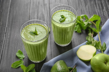 Glasses of tasty avocado smoothie on wooden background