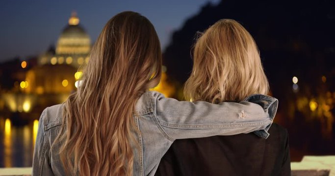 Portrait of two female besties holding each other while out exploring Rome at night, Young brunette with her arm around her blonde friend's shoulder in Rome, Italy, 4k