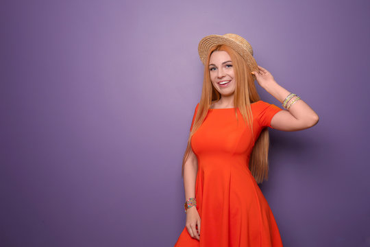 Beautiful young woman in hat on color background