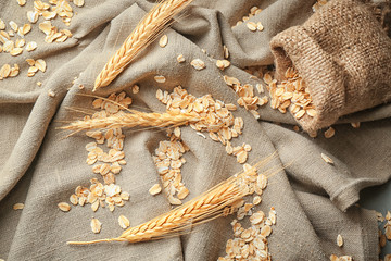 Fototapeta na wymiar Scattered oatmeal flakes and spikelets on table