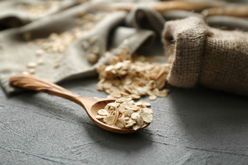 Sack and wooden spoon with oatmeal flakes on table