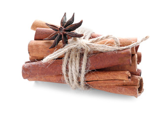 Tied cinnamon sticks and anise star on white background