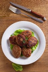 Patties or homemade burgers on white plate. View from above, top studio shot