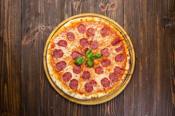 Pizza pepperoni with mozzarella cheese, salami and arugula on wooden background