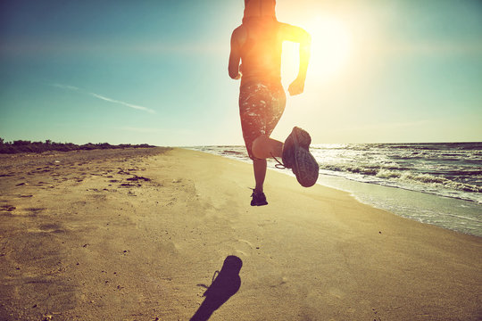 Fitness Woman Running By The Beach At Sunrise. Healthy Active Lifestyle Girl Exercising Outdoors