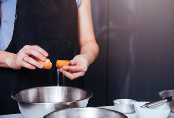 Woman girl baker in kitchen cooking whisk egg to bowl